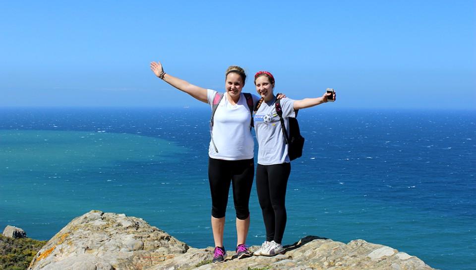 Two students on top of a mountain overlooking the ocean