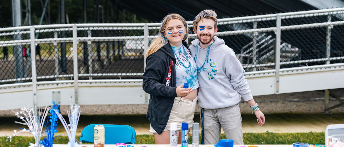 Two students pose at a merch table